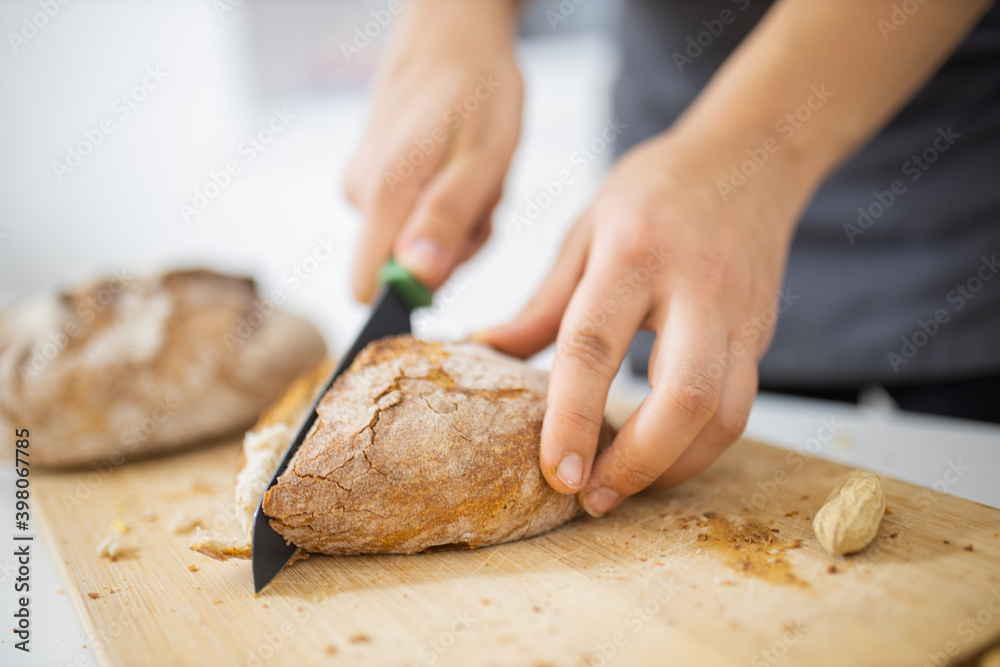 Female hands slicing bread on a cutting board Female hands slicing bread on a cutting board