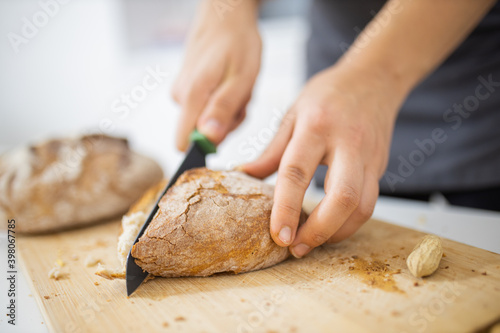 Female hands slicing bread on a cutting board