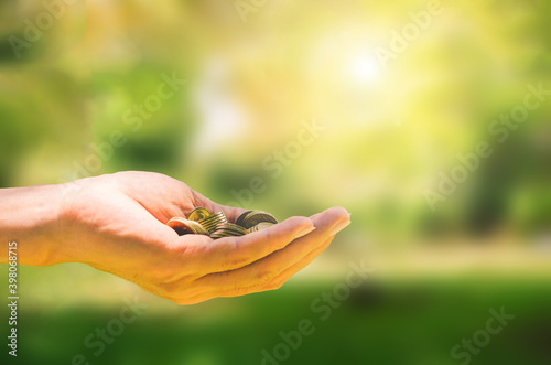 business concept. hands of business man hold money coin wiht green blur background for financial saving and investing growth.