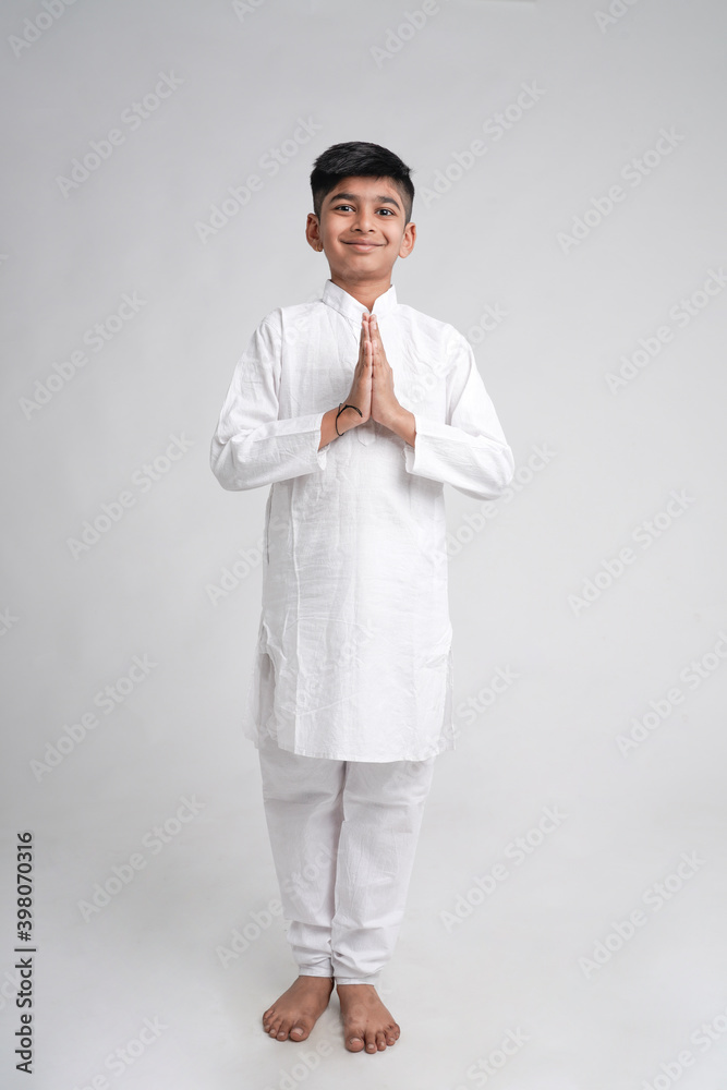 Cute indian little boy in namaste or praying pose over white background
