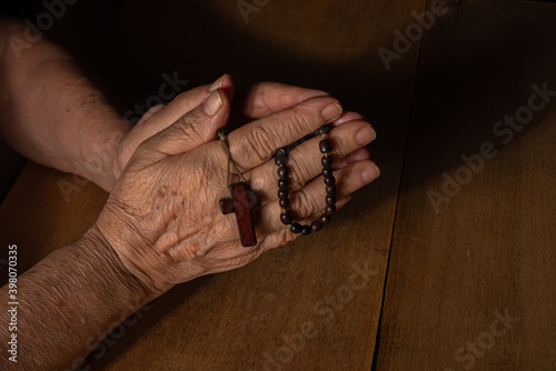 Faith, lady's hands with a third praying over wood, low key photo, selective focus. © Milton Buzon