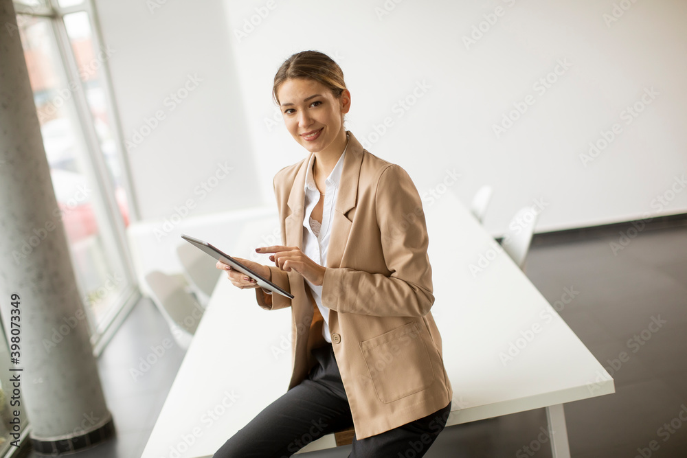 Happy woman manager holding digital tablet and standing in modern office - obrazy, fototapety, plakaty 
