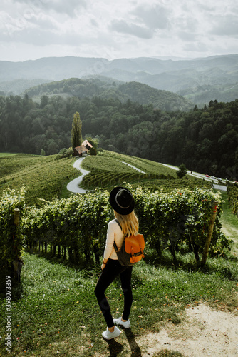 Young girl in hat stands in background of famous road in shape of heart. Vineyard Spicnik near town of Maribor, Slovenia, Europe. photo