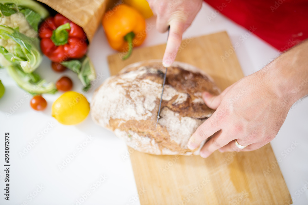 Male hands slicing bread on a cutting board
