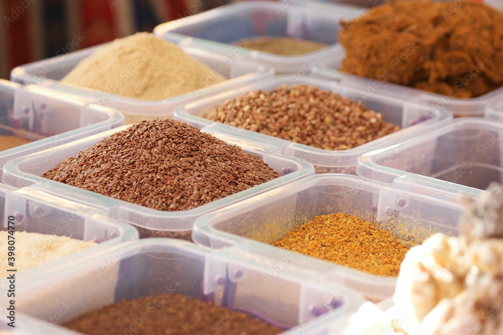 Flax seeds and other healthy seasonings in plastic boxes. Close up of containers with assorted oriental spices.