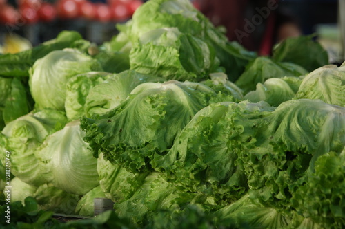 Fresh iceberg lettuce on market stall. Green organic vegetables background. Healthy food concept.