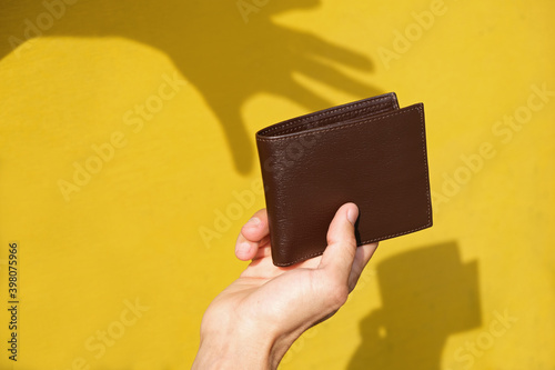 Принти на полотні Shadow of robbers hand on yellow wall trying to steal leather wallet from persons hand