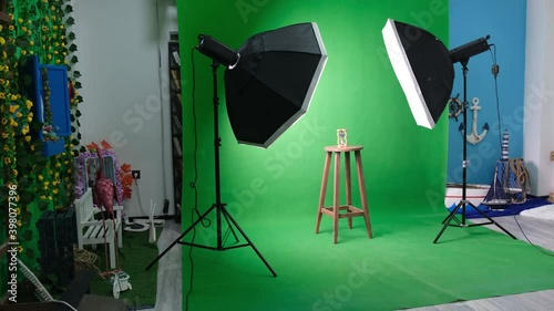 Photo or video studio with two hexagone studio lights. Hourglass on green curtain and fixed chair
