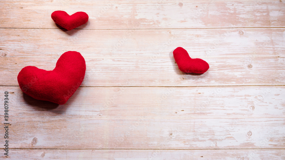 Minimalistic greeting card as gift for Valentines day holiday. Three red toy soft plush hearts on wooden table. Flat background for Valentines day and empty space for lettering or design. Minimalistic greeting card as gift for Valentines day holiday. Three red toy soft plush hearts on wooden table. Flat background for Valentines day and empty space for lettering or design.
