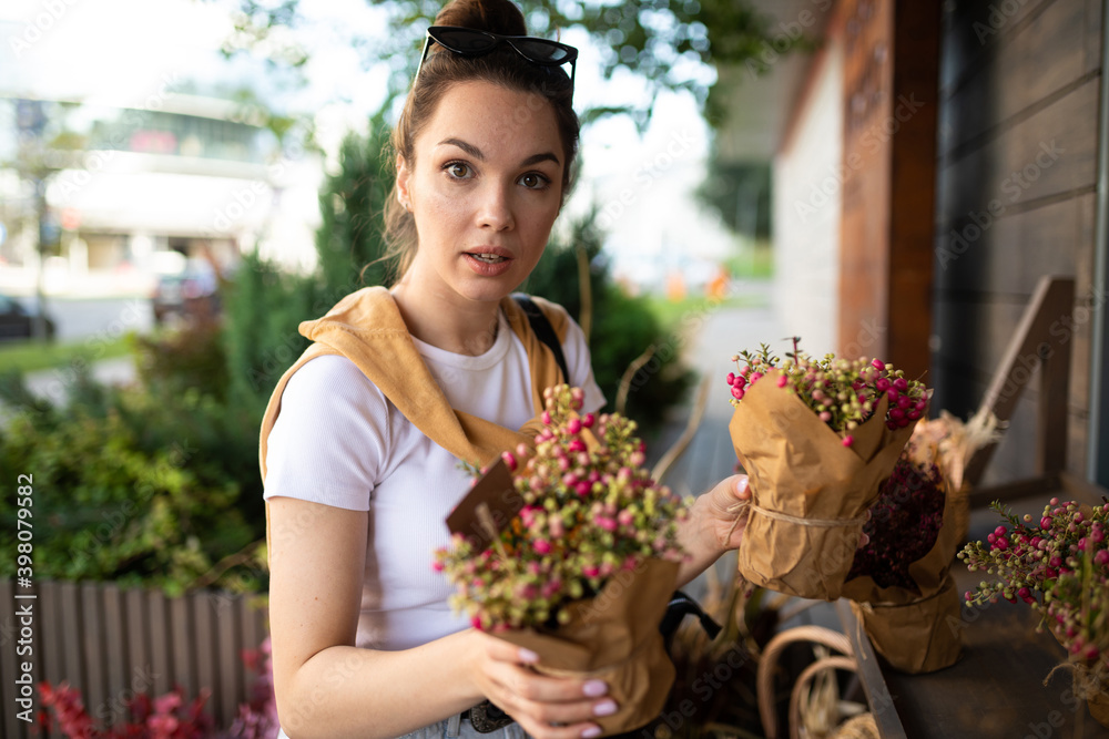 charming young woman buying flowers at garden summer shop