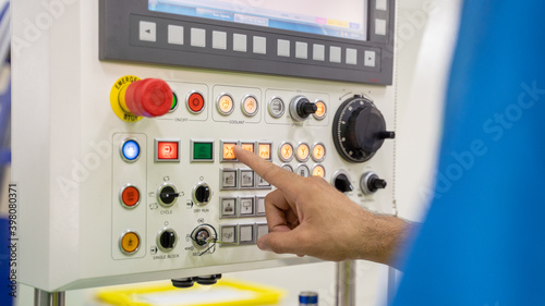 Closeup hand of engineer pushing switch on machine panel in factory.