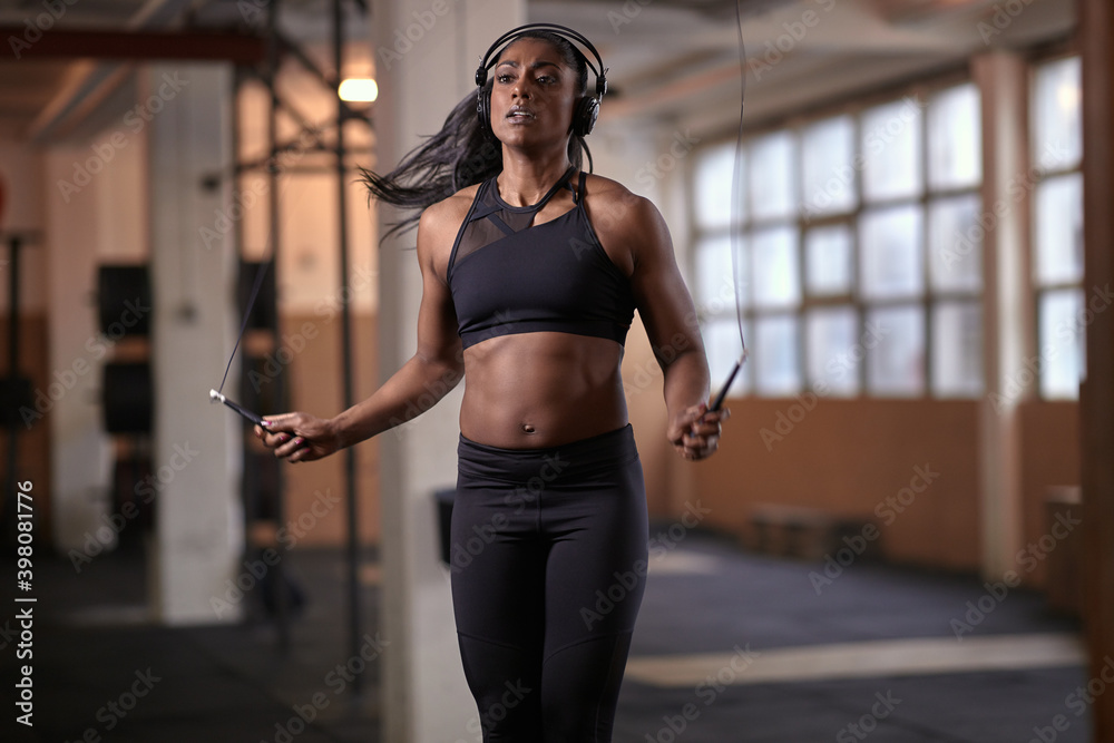 Ethnic female athlete doing jumping rope exercise