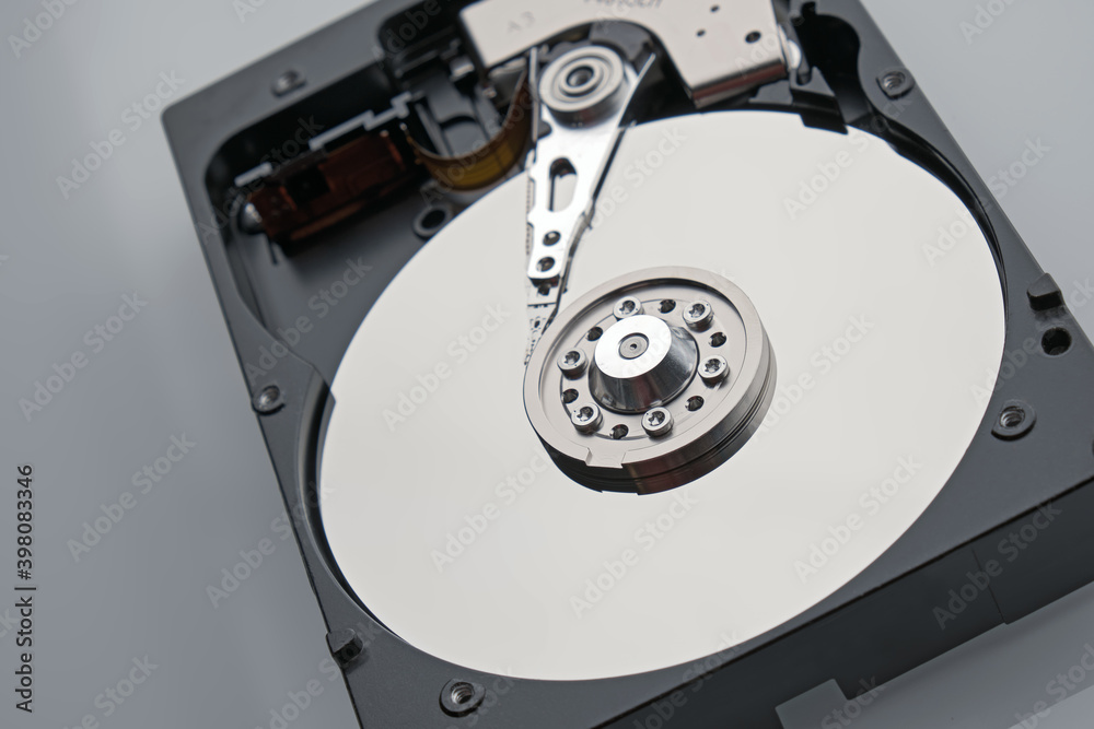 Disassembled HDD macro shot. Clean mirror surface with with magnetic needle on center. Broken hard drive storage and computer equipment on grey background. Disassembled HDD macro shot. Clean mirror surface with with magnetic needle on center. Broken hard drive storage and computer equipment on grey background.