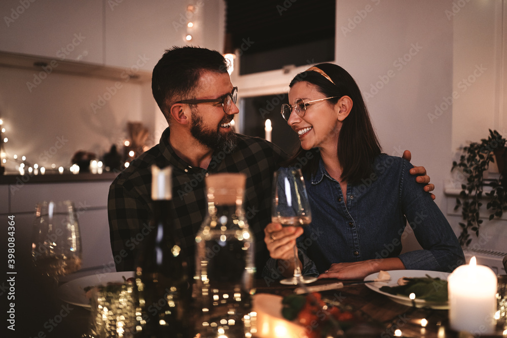 Smiling couple talking together during a candlelit dinner party - obrazy, fototapety, plakaty 