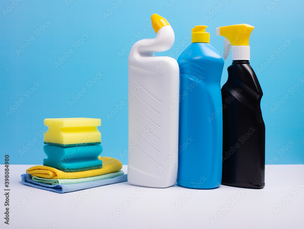Cleaning concept with various plastic bottles canisters and sponges on blue background. Various detergents and the necessary attributes for cleaning Cleaning concept with various plastic bottles canisters and sponges on blue background. Various detergents and the necessary attributes for cleaning