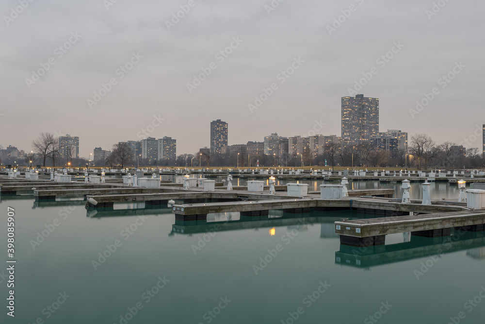 Empty boat docks sitting on calm water with apartment buildings in early evening in Chicago