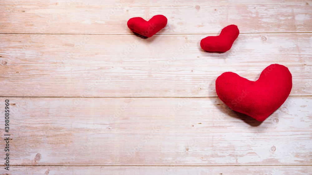 Minimalistic greeting card as gift for Valentines day holiday. Three red toy soft plush hearts on wooden table. Flat background for Valentines day and empty space for lettering or design. Minimalistic greeting card as gift for Valentines day holiday. Three red toy soft plush hearts on wooden table. Flat background for Valentines day and empty space for lettering or design.