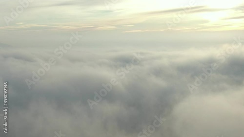 The camera moves slowly over thick clouds to the horizon with the rising sun.