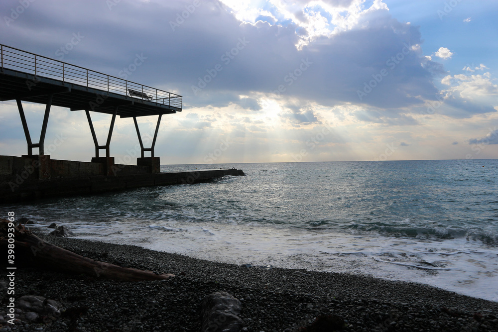 sunset on the pebble beach of Black sea in Crimea with pier on the background sunset on the pebble beach of Black sea in Crimea with pier on the background