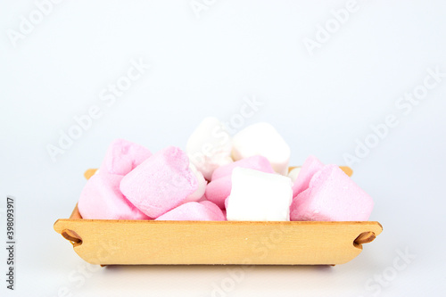 White and pink marshmallows in the shape of hearts laid out on a wooden tray and isolated on a white background