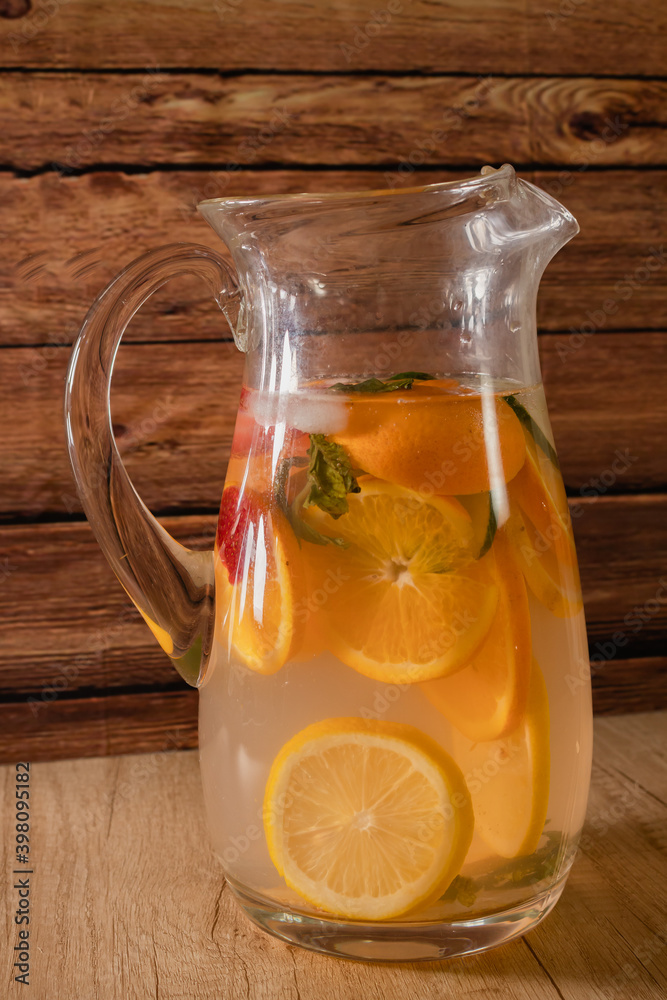 Large glass pitcher with citrus flavored water and homemade lemonade. Glass or jar with drink, lid and straw. Freshness, health and non-alcoholic drinks concept. Large glass pitcher with citrus flavored water and homemade lemonade. Glass or jar with drink, lid and straw. Freshness, health and non-alcoholic drinks concept.