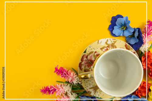 Cozy design  tea set and decorative flowers on a yellow background  copy space  top view  flat lay with white border