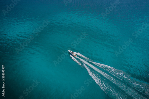 Top view of a white boat sailing to the blue sea. Drone view of a boat. Aerial view luxury motor boat. Drone view of a boat the turquoise clear waters.