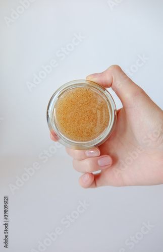 Young woman holding a glass transparent jar of face and body scrub. Glass Cosmetic Jar Mockup