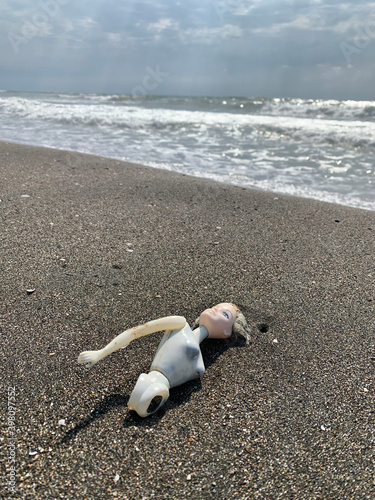 Plastic pollution on beaches, toy doll