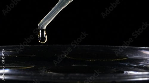 Putting perfumed oil on clear water, black background -close up