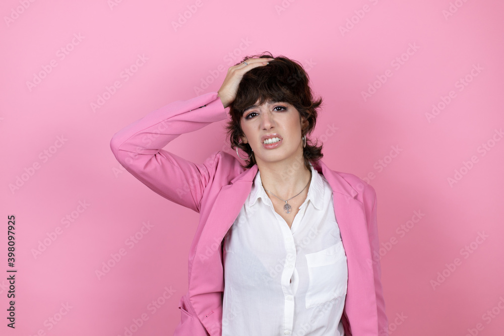 Young business woman over isolated pink background putting one hand on her head smiling like she had forgotten something Young business woman over isolated pink background putting one hand on her head smiling like she had forgotten something