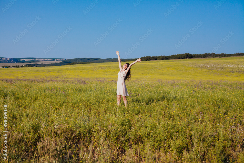 Beautiful woman in light dress walks on the field with flowers Beautiful woman in light dress walks on the field with flowers