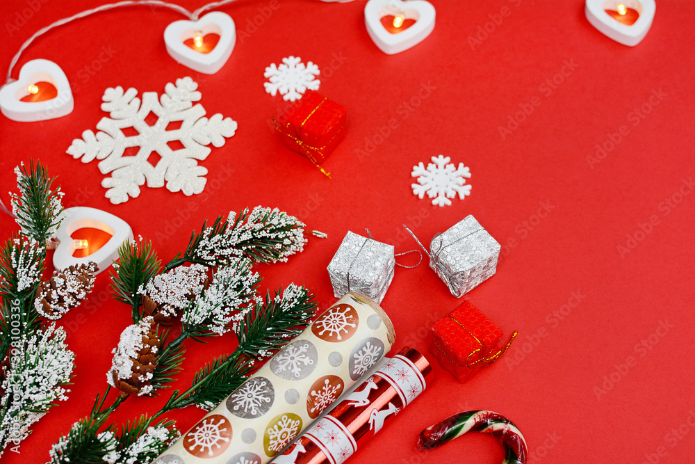 Gift box, wrapping paper, fir branch and garland on a red background. Flat lay. Close-up