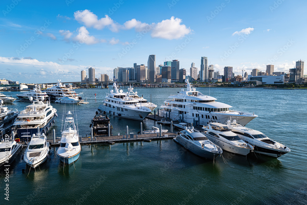 Glowing Yacht Marina. Drone panoramic birds eye view yachts motorboats sailing ships nautical vessels docked in a row at port of Miami. Aerial of marina and green bay.