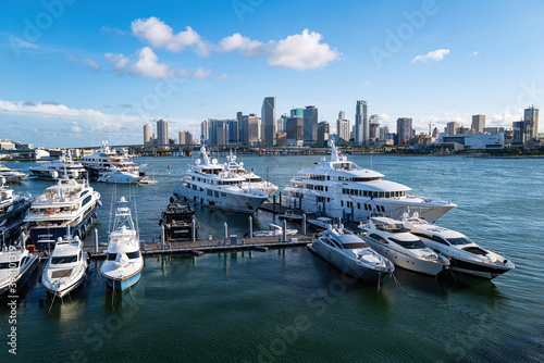 Glowing Yacht Marina. Drone panoramic birds eye view yachts motorboats sailing ships nautical vessels docked in a row at port of Miami. Aerial of marina and green bay. © Tverdokhlib
