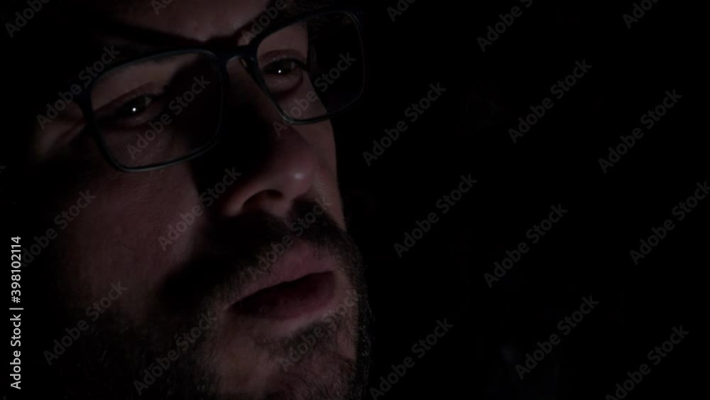 Bearded Man With Eyeglasses Smoking Cigarette In The Dark - extreme close up Bearded Man With Eyeglasses Smoking Cigarette In The Dark - extreme close up