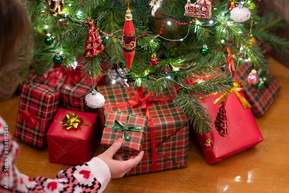 Woman putting gift box under christmas tree. Presents for family.