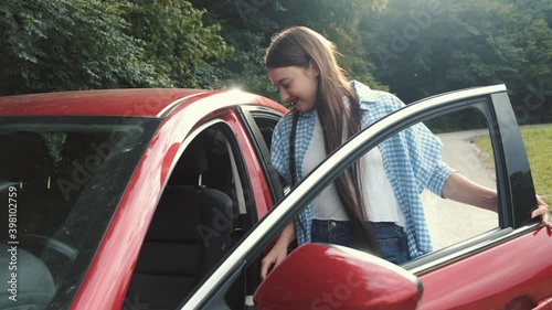 A beautiful young lady is going to her vehicle. She is sitting in the car and readu to go. Women at the steering wheel.