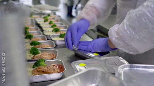 Female cook packing aviation catering food portion close up