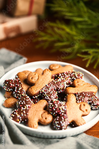 Plate of gingerbread man cookies with chocolate and anise balls. With gray napkin, blurred light background, gifts and Christmas atmosphere. Copy Space