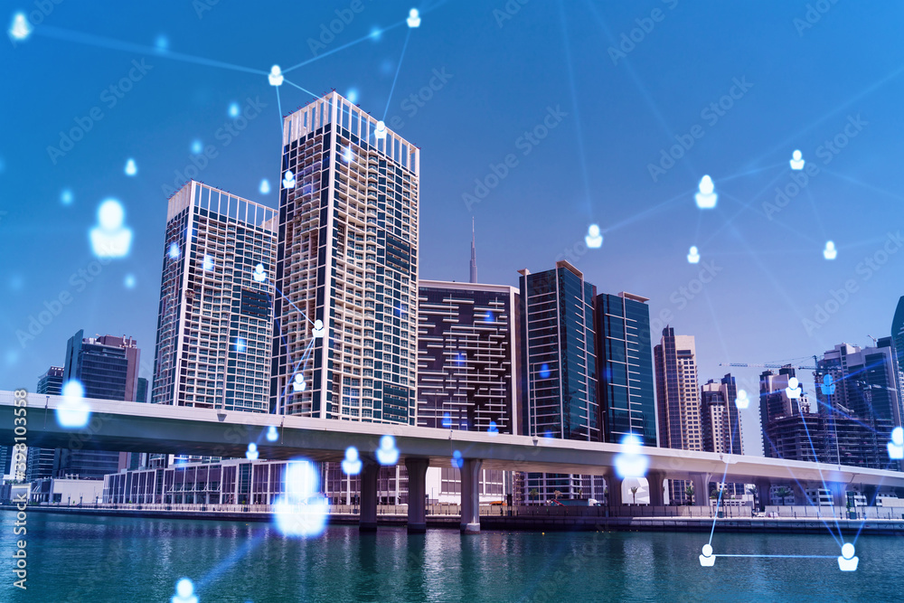 Fototapeta premium Skyscrapers of Dubai business downtown. International hub of trading and financial services. Social network icons hologram, concept of people connection. Double exposure. Dubai Canal waterfront.