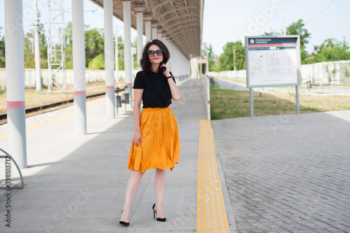 Beautiful brunette in a yellow skirt at the train station