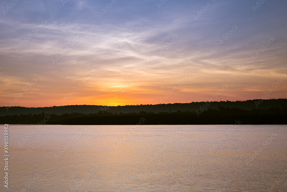 Dreamy scene of sunrise and dawn with a colorful sky in the background and water in the foreground. Image depicting tranquility and calm with copyspace 