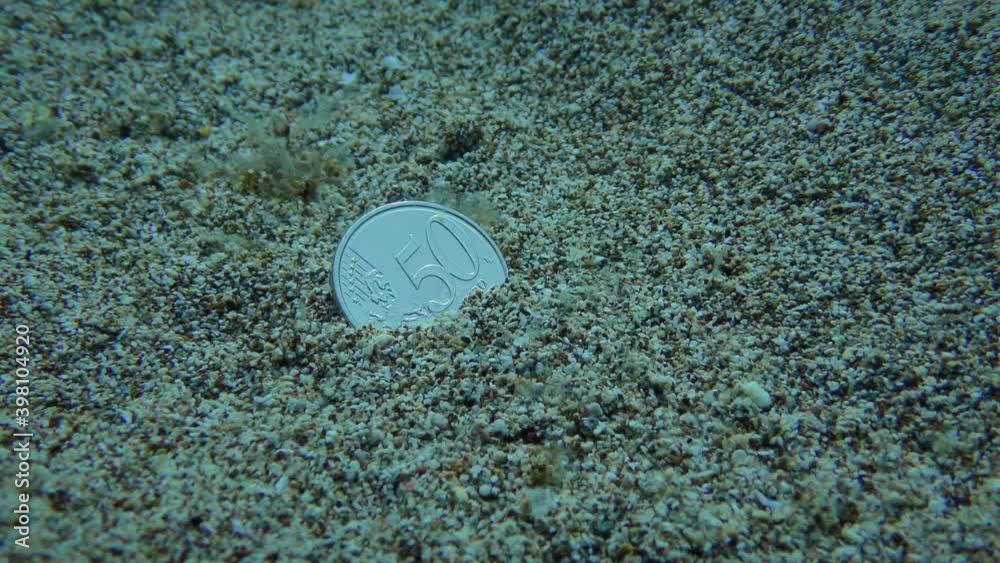 Custom tourists throw a coin in the sea to return to this place: a coin on the sandy bottom. Custom tourists throw a coin in the sea to return to this place: a coin on the sandy bottom.