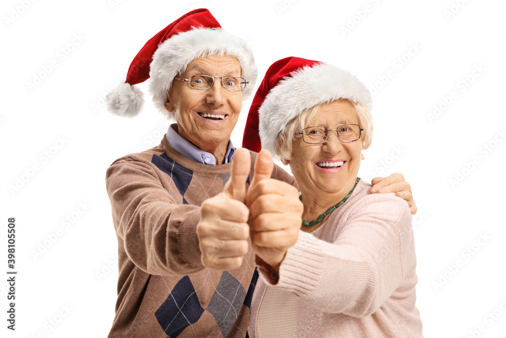 Elderly couple with christmas hats making a thumb up gesture