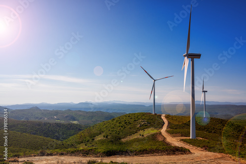 Reflections of the sun's rays on wind turbines in a mountain wind farm in Sardinia. Renewable energy concept, green energy generation. Energy industry.