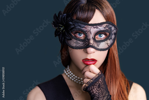Beautiful girl with long brown hair with black mask on a dark background