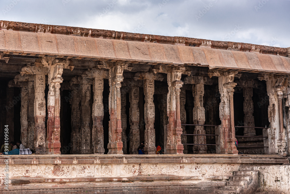 Fototapeta premium Hampi, Karnataka, India - November 4, 2013: Virupaksha Temple complex. Columned side of courtyard in front of Shiva sanctum is brownm rusty stone and offers shade for visitors.