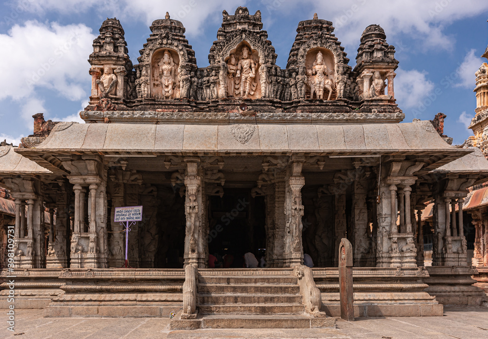 Hampi, Karnataka, India - November 4, 2013: Virupaksha Temple complex. Frontal viw on brown stone Mandapam in front of Shiva Sanctum under blue cloudscape. 