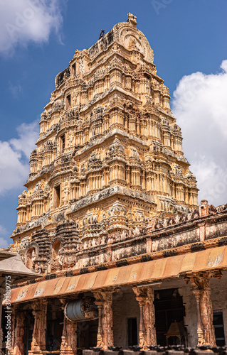 Hampi, Karnataka, India - November 4, 2013: Virupaksha Temple complex. Closeup of yellow stone Vimanam on top of Shiva Sanctum under blue cloudscape. 